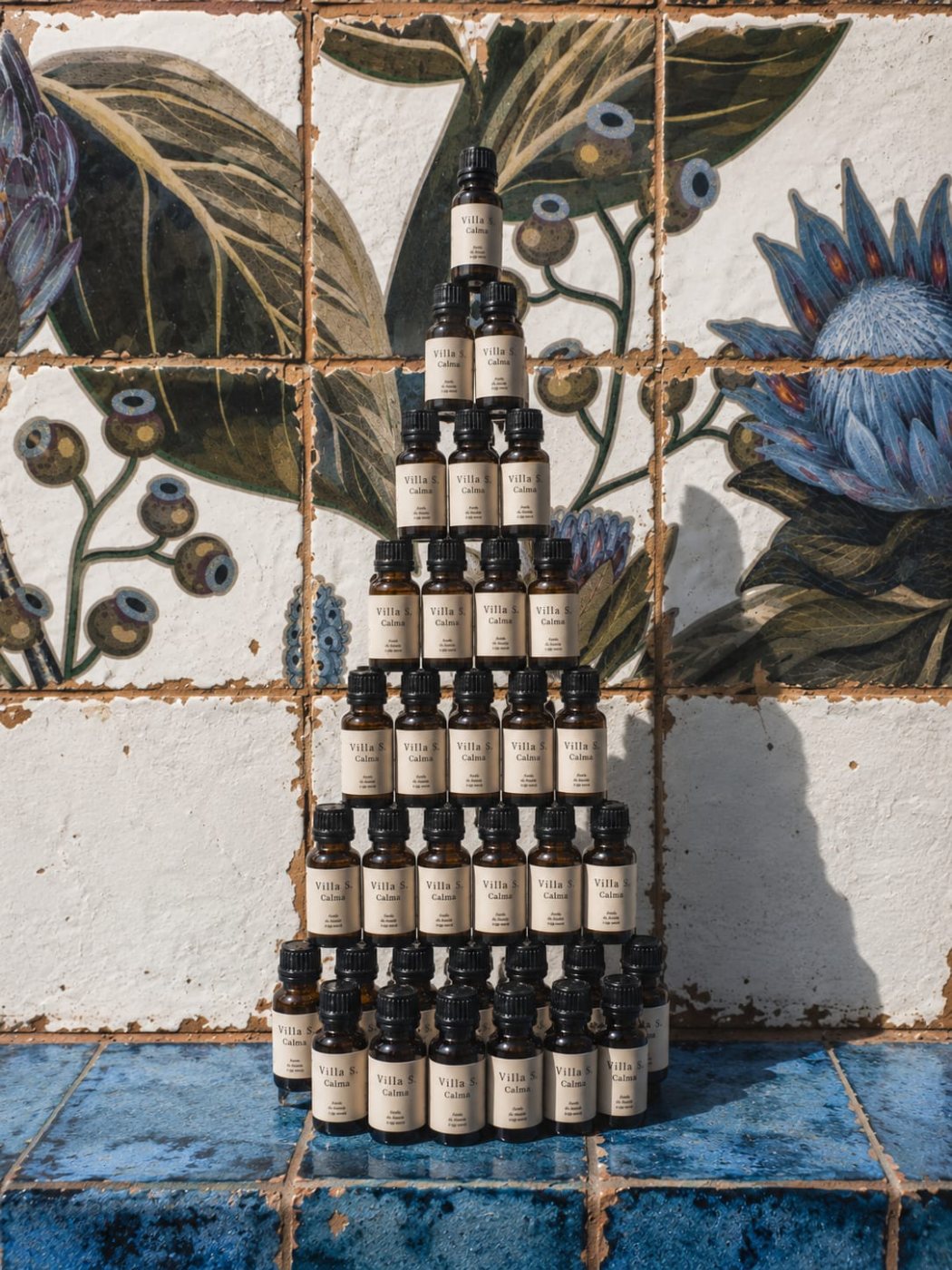 A tower of Calma bottles against the painted tiles